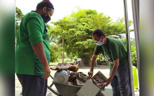 Azman (kanan) memeriksa perkakas rumah yang rosak akibat fenomena kepala air di Kampung Singkir Genting, Kedah.