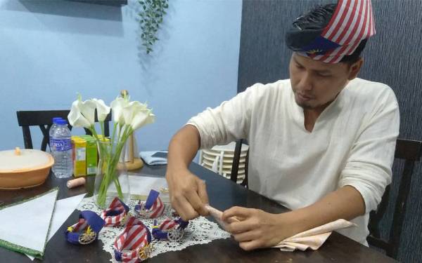 Shahrolnizam menunjukkan cara melipat kain untuk dijadikan tanjak.