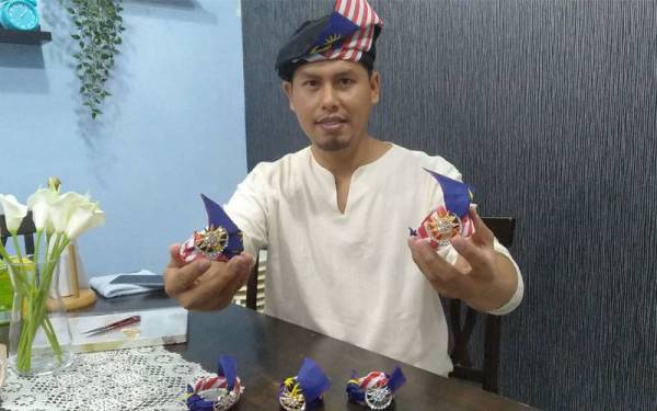 Shahrolnizam menunjukkan tanjak Jalur Gemilang mini yang dihasilkan sempena sambutan bulan kemerdekaan.