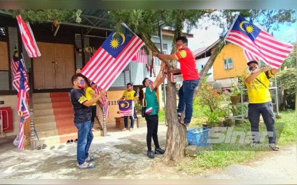 Anak-anak muda dari Pasir Pekan ini bergotong-royong menghias halaman rumah dengan Jalur Gemilang.