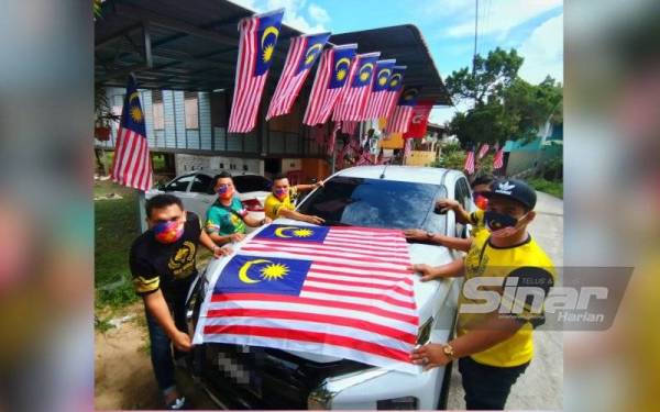 Murtadhatumizi (kiri) dan rakan-rakannya menghias kenderaan dengan Jalur Gemilang bagi menyemarakkan sambutan bulan kemerdekaan.