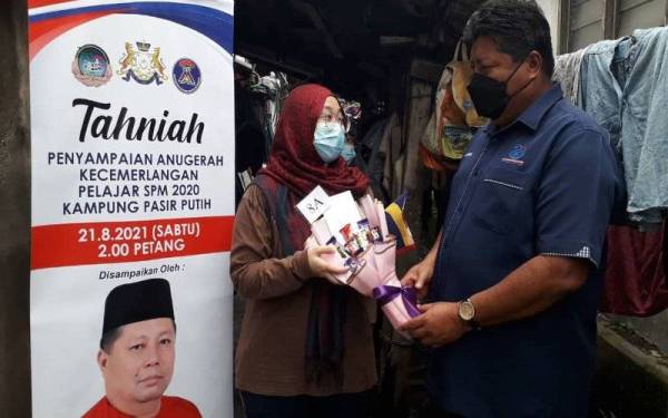 Mazlan menyampaikan sumbangan kepada pelajar cemerlang SPM 2020, Nur Asida Saiful Hadi dalam program Penyampaian Anugerah Kecemerlangan Pelajar Sijil Pelajaran Malaysia (SPM) 2020 di Kampung Pasir Putih, Pasir Gudang pada Sabtu.