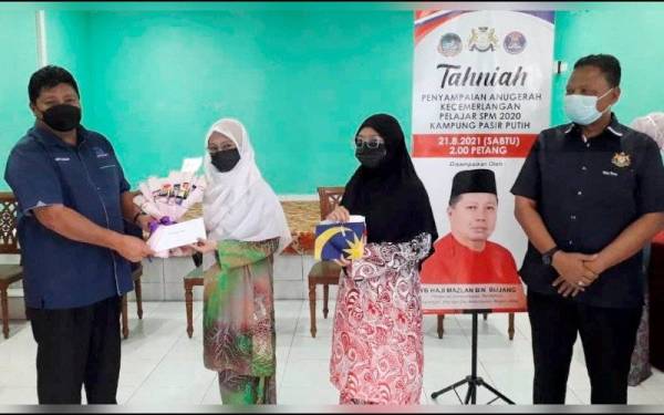 Mazlan (kiri) menyampaikan sumbangan kepada pelajar cemerlang SPM 2020, Siti Hasnah Ambomiri dalam program Penyampaian Anugerah Kecemerlangan Pelajar Sijil Pelajaran Malaysia (SPM) 2020 di Kampung Pasir Putih, Pasir Gudang pada Sabtu.