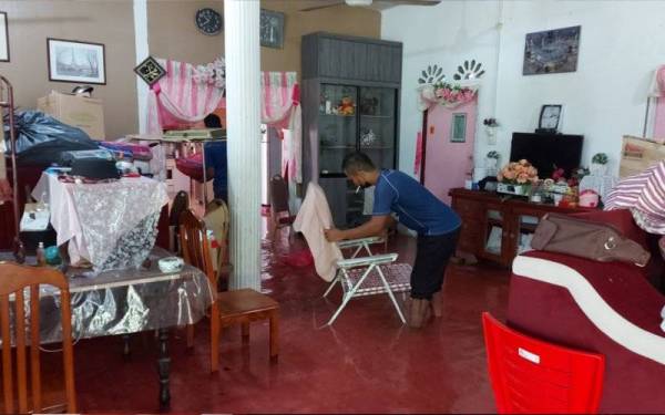 Mohammad Noor Fadzilah mengemas barang-barang rumah setelah dinaiki air sejak Jumaat. 