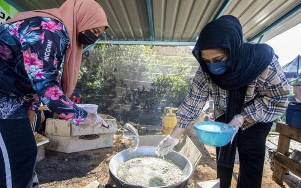Aina Fatini (kanan) menggoreng peria yang telah dipotong untuk menghasilkan kerepek peria ketika ditemui di rumahnya di Kampung Kubang Palas, Banggu. - Foto Bernama