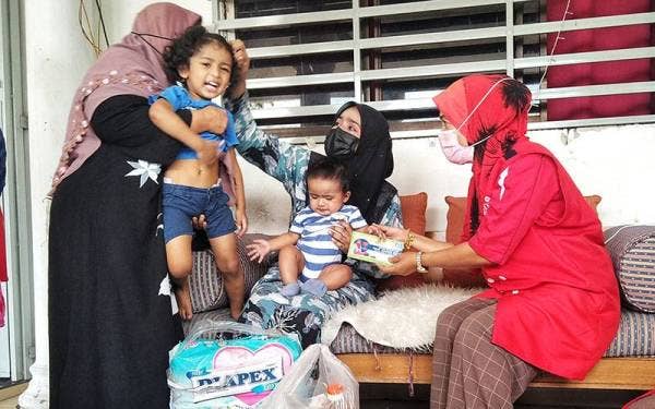 Juhanis (kanan) menyampaikan sumbangan kepada Nur Haslin semasa kunjungan Skuad Sayang Wanita UMNO Bahagian Temerloh pada Sabtu.