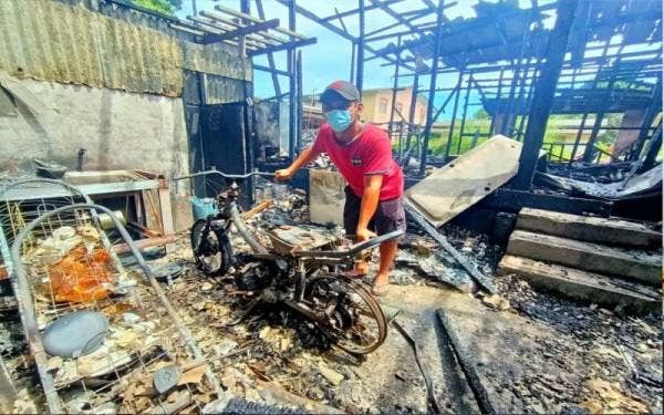 Mohd Asyraf menunjukkan motosikal yang merupakan kenderaan utama mereka sekeluarga terbakar.