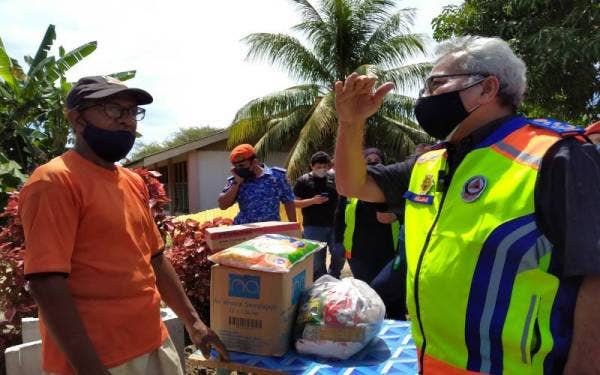 Mohd Redzuan (kanan) ketika meninjau dan menyampaikan sumbangan kepada mangsa terjejas bencana fenomena kepala air di Kampung Permatang Keramat, Yan pada Ahad.