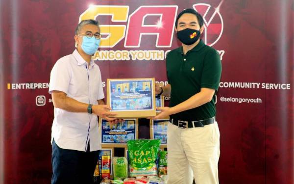 Tengku Amir Shah (kanan) berkenan menerima bakul makanan daripada Tengku Zafrul Tengku (kiri) sebagai gimik penyerahan sumbangan bakul makanan kepada Yayasan Raja Muda Selangor (YRMS) di Pusat Latihan Selangor FC, pada Ahad. -Foto Bernama 