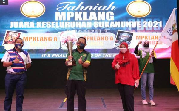 Ahmad Fadzli (tengah) bersama Piala Pusingan Keseluruhan SUKANUNVE 2021 yang diserahkan Zamri (kiri) di Dewan Hamzah, Klang.
