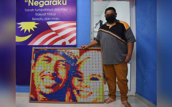 Pengurus Pusat Internet Kampung Pianggu Zabli Ab Hadi, 35, bergambar bersama potret Shamira Muhamad atau Shuip Sepahtu dan Allahyarhamah Siti Sarah Raisuddin yang dihasilkannya menggunakan kiub rubik. - Foto Bernama