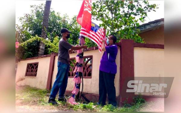 Pengerusi Pertubuhan Kebajikan Penduduk Mukim Parit, Wan Azizi Wan Ab Ghani (kiri) dan penduduk, Tuan Mohd Nor Tuan Yahya,56, menggantungkan Jalur Gemilang supaya berkibar bagi membangkitkan semangat patriotisme sempena bulan Kemerdekaan ke-64 pada bulan Ogos ini.
