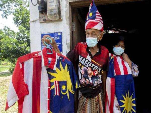 Pok Dir ditemani isteri Hasmah Yusof, 56, menunjukkan baju Jalur Gemilang ketika ditemui di rumahnya di Kota Jembal hari ini. - Foto Bernama