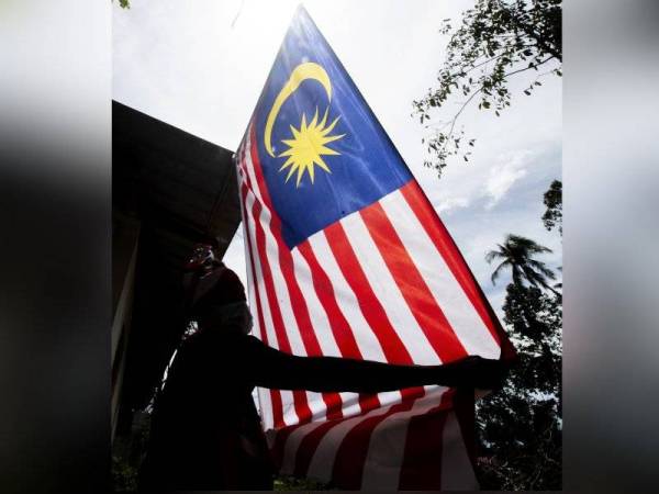 Pok Dir dilihat tetap bersemangat membuat persiapan bagi menyambut Hari Kebangsaan dengan memasang Jalur Gemilang di rumahnya di Kota Jembal hari ini. - Foto Bernama