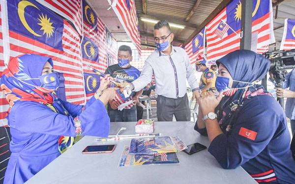 Ahli Jawatankuasa Team Sahabat Man 23 Jam, Mohd Azman Mohd Ghani (dua, kanan) menghadiahi Jalur Gemilang kepada pelanggan yang menjawab teka-teki dengan betul serta memberi makanan percuma bagi menyemarakkan semangat patriotik menjelang sambutan Hari Kebangsaan ke-64 pada Isnin. - Foto Bernama