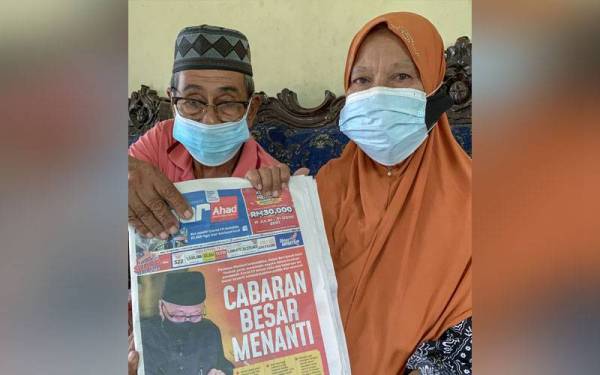 Che Rahimah bersama suami, Nordin menunjukkan keratan akhbar pelantikan Datuk Seri Ismail Sabri Yaakob sebagai Perdana Menteri Ke-9 Malaysia ketika ditemui di rumahnya di Kampung Gertak Lembu, Salor pada Isnin. Foto Bernama