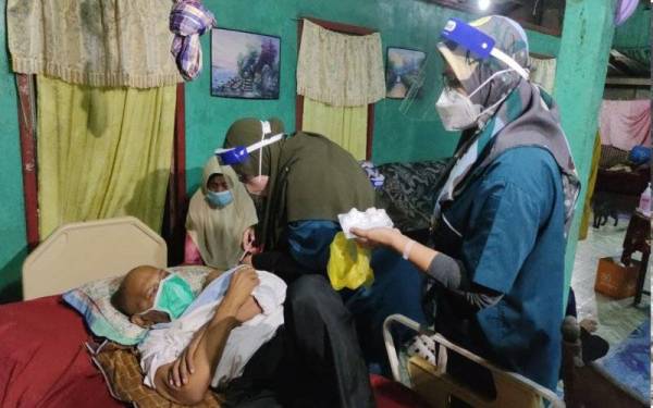 Petugas PPV UniSZA memberi suntikan kepada Rozelan yang terlantar akibat angin ahmar di rumahnya di Kampung Teluk Pasu pada Selasa.