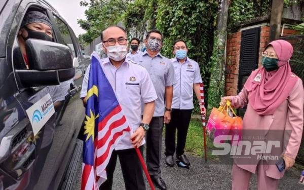 Fat Full menyerahkan Jalur Gemilang kepada penduduk selepas melancarkan Pertandingan Kempen Kibar Jalur Gemilang 2021 di KRT Peringkat Negeri Johor di KRT Nong Chik, Johor Bahru pada Selasa.