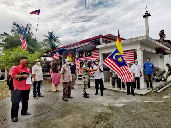 Mustafa (depan, dua dari kanan) menyerahkan Jalur Gemilang kepada wakil ATM di Surau Kampung Dusun Nyior, Seremban pada Rabu.
