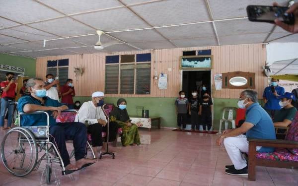 Al-Sultan Abdullah (duduk dua, kanan) dan Tengku Hassanal (duduk, kanan) beramah mesra dengan keluarga Wahab Ali, 86, ketika Seri Paduka berkenan menziarah dan menyampaikan sumbangan kepada penduduk kurang berkemampuan di Kampung Tanjung Pulai pada Rabu. - Foto Bernama