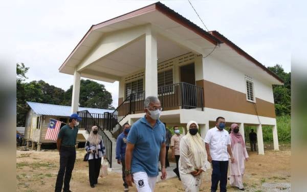 Al-Sultan Abdullah (tengah) dan Tengku Hassanal (kiri) berkenan melihat sekitar kawasan rumah bersama penerima rumah, Norhasnah Md Yunos (tiga, kanan) di Kampung Sungai Ganchong pada Rabu. - Foto Bernama