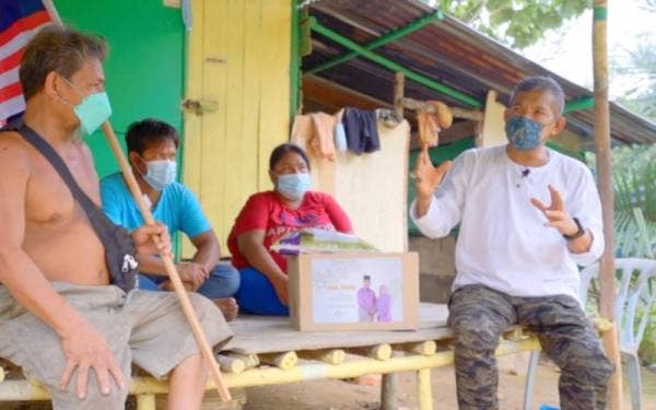 Mohd Yusoff (kanan) ketika menyampaikan sumbangan kepada salah sebuah keluarga orang asli di Bukit Meranti, Jasin.