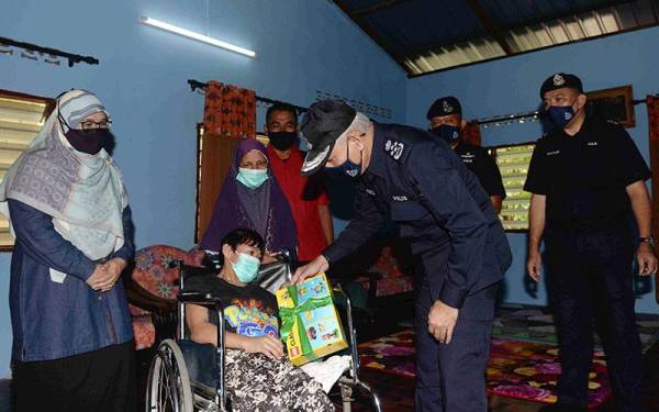 Ketua Polis Negara Datuk Seri Acryl Sani Abdullah (dua, kanan) menyampaikan sumbangan kepada Siti Zahariah Omar, 36, (berkerusi roda), sambil diperhatikan ibunya, Siti Asa Abd Hamid, 72, (dua, kiri) pada Program Op Bantu di Kampung Sidam Kanan, Padang Serai hari ini. - Foto Bernama