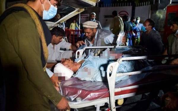 Anggota-anggota perubatan membantu membawa seorang mangsa yang cedera dalam kejadian dua pengeboman di sebuah lapangan terbang di Kabul pada Khamis. - Foto AFP