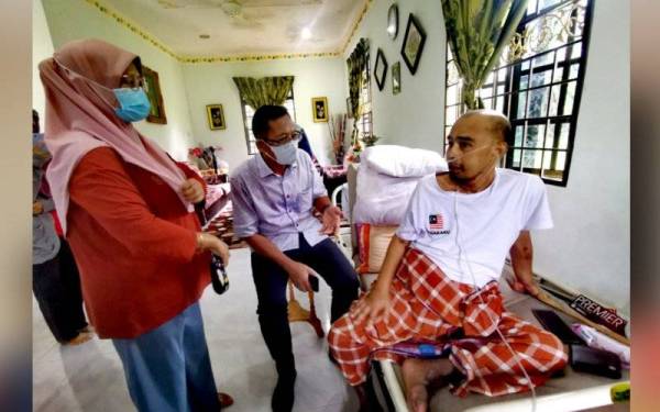 Jasilawati (kiri) mendengar Mustafa (tengah) bertanya sesuatu kepada Suhaimi di rumahnya di Kampung Daching Hulu, Seremban pada Khamis.