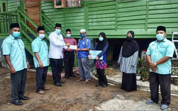 Mohd Nazri (tiga,kiri) menyampaikan sumbangan kepada waris pelajar, Ahmad Fisal Md Thahir ketika menziarahi keluarga berkenaan di Yan pada Jumaat.