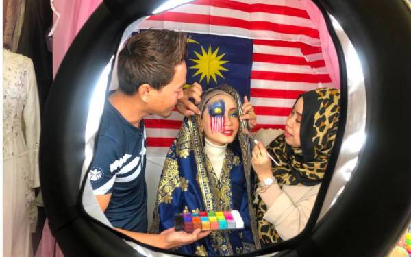 Faridatul Aswani (kanan) dan suami, Mohd Harmizi Mahmood, 44, sedang menyolek anaknya, Qaseh Humaira Mohd Harmizi, 15.