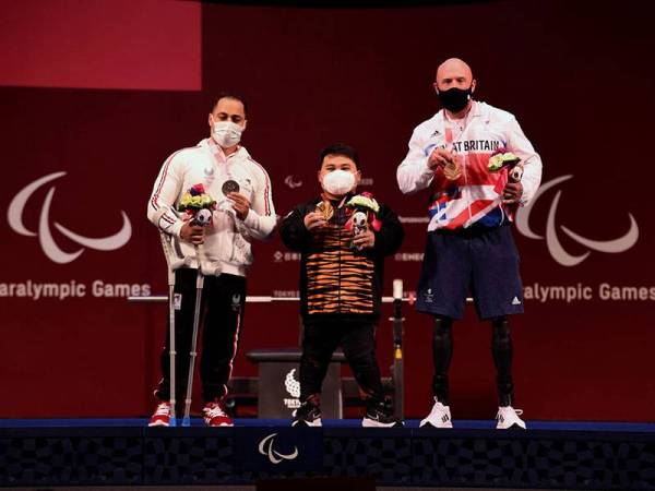 Atlet powerlifting paralimpik negara, Bonnie Bunyau Gustin (tengah) bergambar dengan atlet dari Mesir dan Great Britain, Attia Mahmoud (kiri) dan Yule Micky setelah berjaya meraih pingat emas pertama negara bagi kategori 72 kilogram (kg) pada Kejohanan Sukan Paralimpik Tokyo 2020 di Tokyo International Forum hari ini.