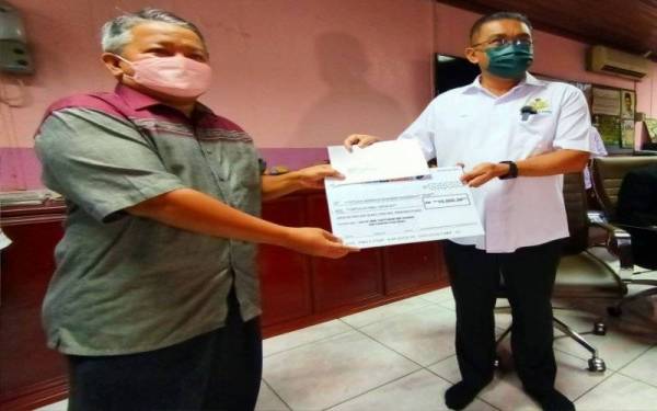 Takiyuddin (kanan) menyampaikan sumbangan kepada penerima semasa melancarkan Kempen Kibar Jalur Gemilang Sempena Sambutan Ulang Tahun Kemerdekaan Negara Ke-64 di Kota Bharu pada Sabtu.