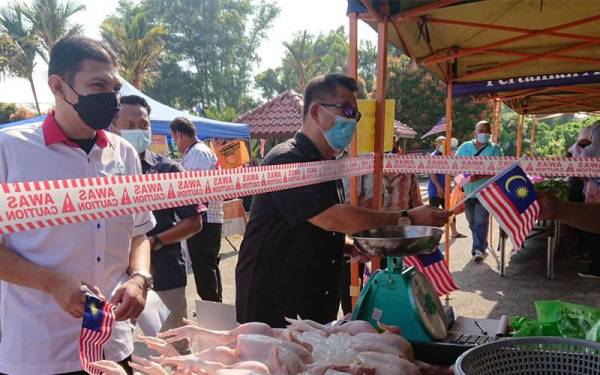 Muhammad Jailani menyerahkan Jalur Gemilang kepada peniaga ketika Program Pasar Segar Terkawal di Jawatankuasa Pembangunan dan Penyelarasan Dewan Undangan Negeri (Japerun) Rembia di sini pada Sabtu.