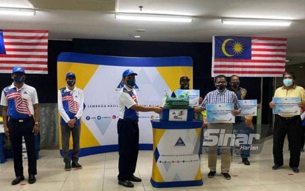 Kamarudin (tiga dari kiri) menyampaikan sumbangan bakul makanan kepada salah seorang wakil penduduk untuk diagihkan kepada penduduk terkesan Covid-19 di sekitar Klang.