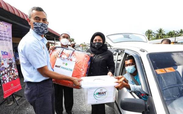 Haslina (tengah) menyampaikan bantuan Bakul Makanan MAFI Prihatin kepada petani yang terjejas.
