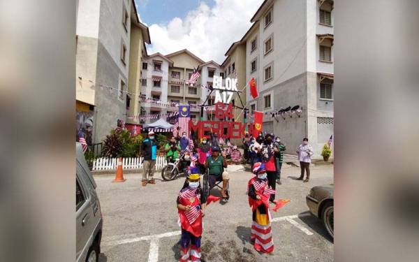 Khairulnisa Batrisya, 8 (kanan) dan adiknya, Amar Haziq Kamarul Zaman, 6, memperagakan pakaian Jalur Gemilang bersama penduduk meraikan sambutan kemerdekaan negara.