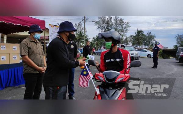 Azman (dua dari kiri) menyampaikan lesen sampan kepada seorang nelayan secara pandu lalu di Pengkalan Merchang, Marang pada Ahad.