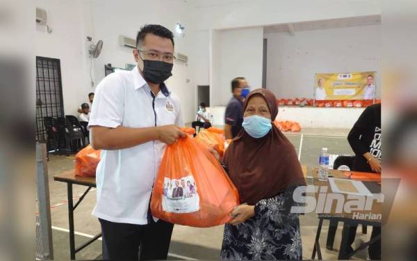 Mohd Hairi (kiri) menyampaikan sumbangan kepada seorang penerima program pemberian 1,000 bakul makanan kepada masyarakat di Johor Bahru pada Ahad.
