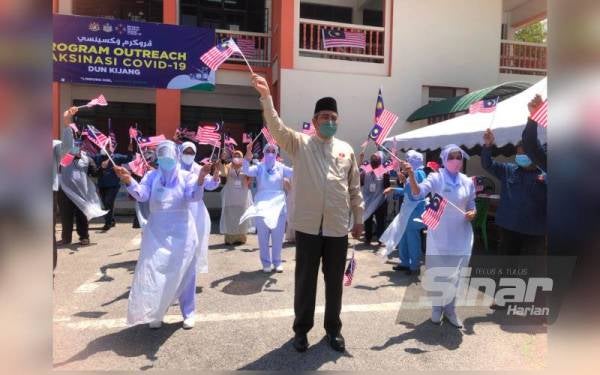 Exco Kerajaan Tempatan, Perumahan dan Kesihatan Kelantan, Dr Izani Husin (tengah) mengibarkan Jalur Gemilang ceria bersama-sama petugas barisan hadapan sempena pelancaran Semarak Kemerdekaan Dun Kijang di Program Outreach Vaksinasi Covid-19 di SMU (A) Istiqamah Badang, Kota Bharu pada Ahad.