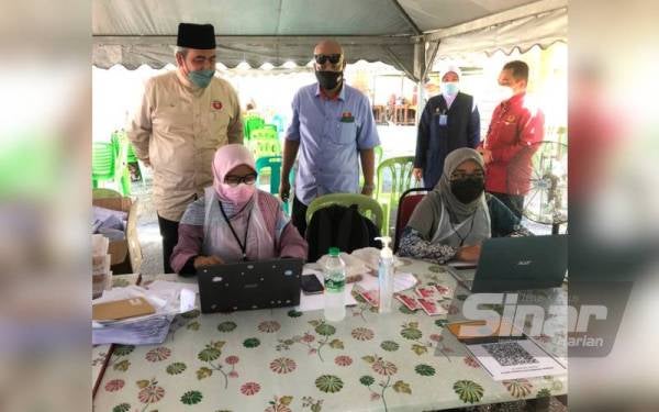 Exco Kerajaan Tempatan, Perumahan dan Kesihatan Kelantan, Dr Izani Husin (kiri) sempat beramah-mesra dengan para petugas di Program Outreach Vaksinasi Covid-19 di SMU (A) Istiqamah Badang, Kota Bharu pada Ahad.