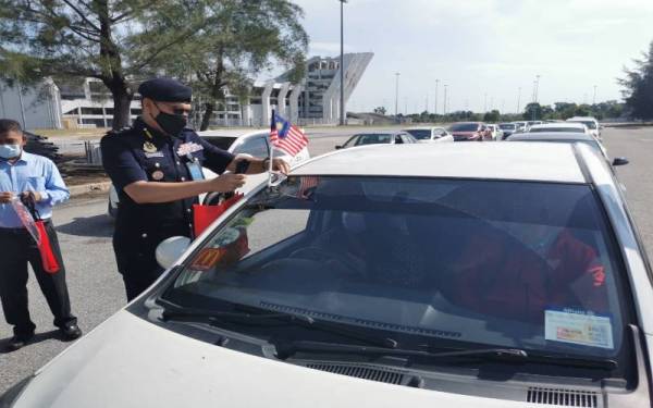 Zulkarnain memasang bendera pada salah sebuah kereta orang awam bersempena Program Semarak Merdeka sempena Sambutan Hari Kebangsaan ke-64, pada Ahad.