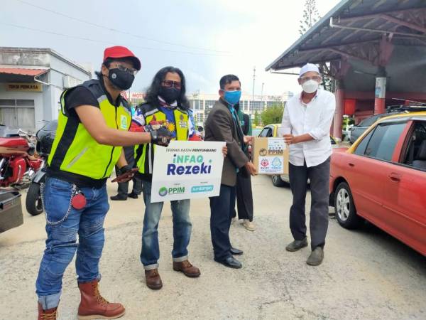 Mohamad Haron (dua dari kanan) menyampaikan sumbangan kotak makanan kepada Zaki (kanan) sambil disaksikan oleh Mohd Razmi (kiri) di Shahab Perdana di sini pada Ahad.