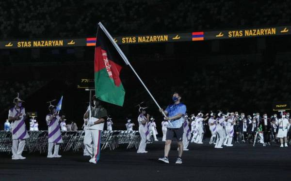 Seorang sukarelawan membawa bendera Afghanistan pada acara pembukaan Sukan Paralimpik Tokyo 2020. -Foto: AFP