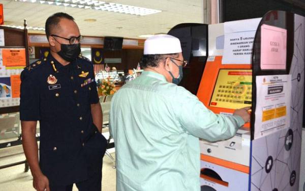 Mohd Amar menggunakan perkhidmatan yang disediakan oleh JPJ Kelantan di Panji, Kota Bharu sambil diperhatikan Hanif Yusabra.