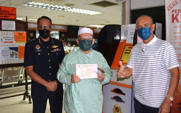 Mohd Amar (tengah) menunjukkan salinan Kad Perakuan Kenderaan (VOC) beliau yang diperoleh dalam tempoh singkat menerusi penggunakan sistem di kios Jabatan Pengangkutan Jalan (JPJ) Kelantan di Panji, Kota Bharu pada Ahad.