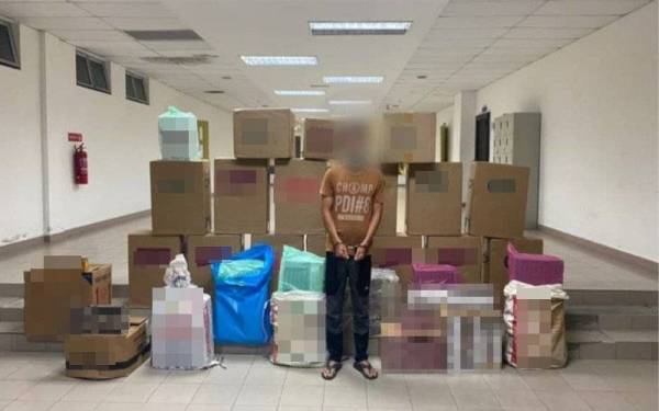 Suspek bersama rokok seludup yang dirampas dalam serbuan di sebuah premis di Parit Yani Yong Peng, Batu Pahat pada Ahad. - Foto ihsan PGA