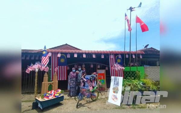 Mohd Sharkawi dan isteri serta anak-anaknya menunjukkan hiasan kemerdekaan di hadapan rumah mereka di Taman Sri Purnama, Pasir Puteh yang dinobatkan sebagai pemenang tempat pertama.