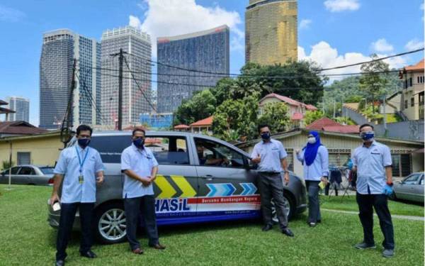 Kamarudin (tiga dari kanan) bersama pasukannya bersiap sedia untuk agihan bekalan bakul makanan.
