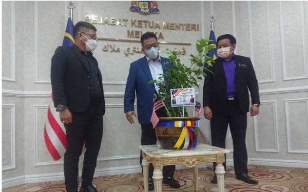 Norhizam (kiri) dan Muhammad Muhaimin ketika penyerahan bunga raya kepada Sulaiman (tengah) di Seri Negeri, Ayer Keroh, di sini, pada Isnin.